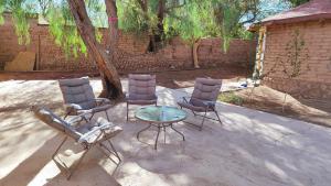 um pátio com três cadeiras, uma mesa e uma árvore em cabañas katchi em San Pedro de Atacama
