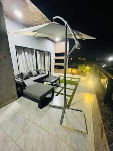 a patio with a couch and a table and umbrella at Serenity Haven:Your Ideal Escape in Lomé