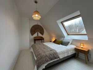 a attic bedroom with a bed and a window at Villa Marius proche de la plage in Ambleteuse