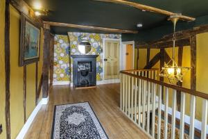 a hallway with a staircase with a fireplace in a house at Luxury 3 Bed Manor House Hot Tub & Cinema in Saffron Walden