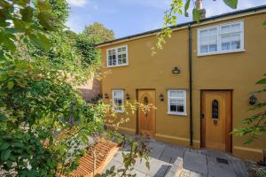 a large yellow house with a wooden door at Luxury 3 Bed Manor House Hot Tub & Cinema in Saffron Walden