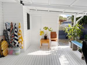 Norah50 meters to the beach Hargraves Beach Cottage的带椅子和冲浪板的白色门廊 更多18张照片