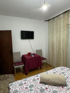 a room with two beds and a table and a tv at Airport home Radinovic in Podgorica