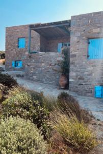 a brick house with blue windows and bushes at Villa Molos in Molos Parou