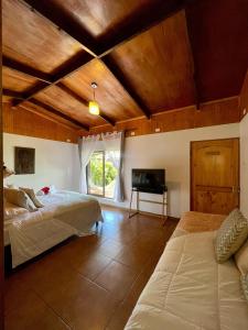 1 dormitorio con 2 camas y TV. en PARAÍSO Sunset Bungallows, en Hanga Roa