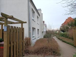 uma cerca de madeira ao lado de uma casa branca em New Apartment mit Terrasse em Hanôver