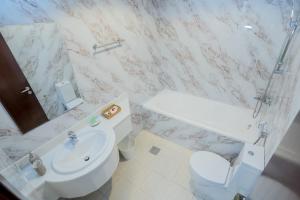 a white bathroom with a toilet and a sink at Vibes by Beds and Company - Room in Dubai
