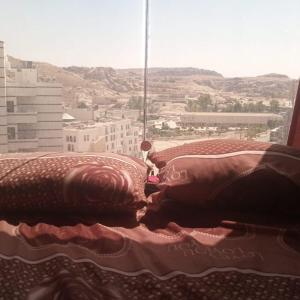 two pillows on a bed with a view of a city at cabin hotel in Ma‘ān