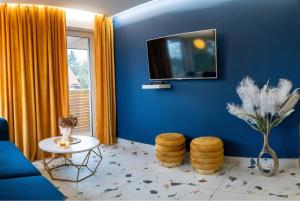 a living room with a blue wall with a tv at Loftowe Pokoje 