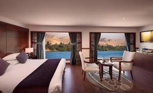 a hotel room with a bed and a table and chairs at NILE CRUISE ULTRA DELUXE in Aswan