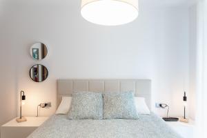 a white bedroom with a large bed with blue pillows at AndBnB I Apartamento con Terraza y Parking in Arinsal