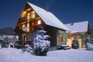 a log cabin in the snow at night at Vila Olimp in Jasenak