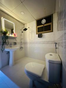 a white bathroom with a toilet and a sink at Sunrise Inn by DSV Property in Abu Dhabi