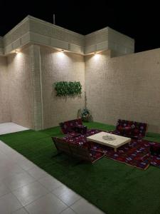 una habitación con sillas y una mesa sobre una alfombra verde en الجود مخيم شقة استراحة بيت, en Khamis Mushayt