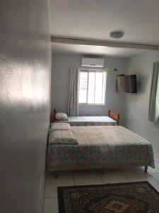 um quarto com 2 camas e uma janela em Kitnet da Fô em Pelotas
