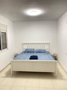1 dormitorio blanco con 1 cama grande con almohadas azules en Spacious penthouse with terrace, en Nahariyya