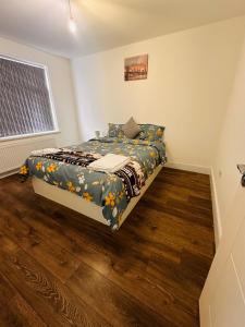 um quarto com uma cama num quarto com pisos em madeira em Lovely Hillingdon Family Holiday Home - 7 bedrooms em Ickenham