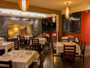 a dining room with white tables and chairs and lights at APU MOUNTAIN LODGE CUSCO in Cusco