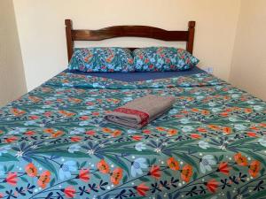 a bed with a flowered comforter with a towel on it at Casa no francês! in Marechal Deodoro +34 photos