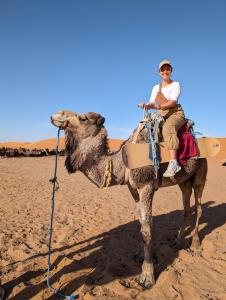 Eine Frau, die auf einem Kamel in der Wüste reitet. in der Unterkunft Traditional Riad Merzouga Dunes in Merzouga