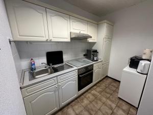 a kitchen with white cabinets and a sink and a refrigerator at Apartment58 in Wiehl