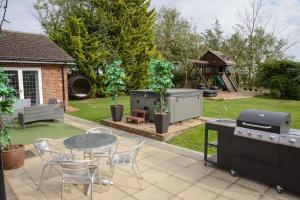 a patio with a grill and a table and chairs at Deluxe 2/3 Bed, Hot Tub, Sky Tv in Great Sampford