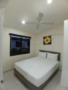 a white bed in a bedroom with a ceiling fan at New Door Apartments in Nadi