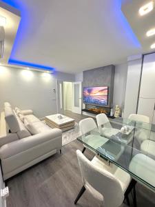 ein Wohnzimmer mit einem Glastisch und weißen Stühlen in der Unterkunft APARTAMENTO LUXURY in Madrid