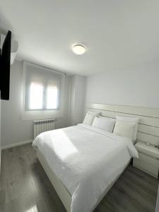 ein weißes Schlafzimmer mit einem weißen Bett und einem Fenster in der Unterkunft APARTAMENTO LUXURY in Madrid + 18 Fotos