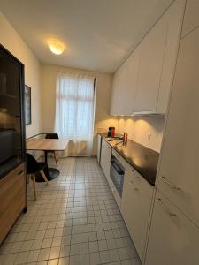 a small kitchen with white cabinets and a table at Apartments by DASBREITEHOTEL in Basel