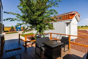 a deck with chairs and a table and a building at Zion Adventure Tiny Home, Cozy Fireplace & Deck in Apple Valley