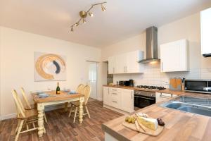 a kitchen with white cabinets and a table with chairs at Miners cottage DH1 Bungalow Free Parking Longstay in Sheepscar