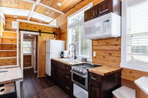 Harrington Tiny House في Apple Valley: مطبخ بجدران خشبية وأرضية خشبية