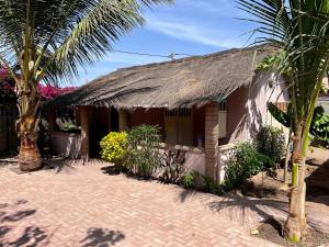 a house with a thatched roof and a palm tree at Amas Bungalow with internett in Batukunku
