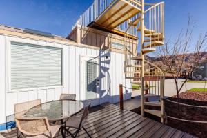 a wooden deck with a glass table and a spiral staircase at Zion Stay, Scenic Tiny Home & Sunset Views in Apple Valley