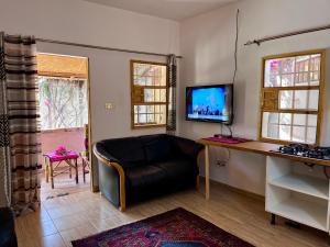 a living room with a couch and a television at Amas Bungalow with internett in Batukunku
