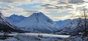 a snowy mountain range with a lake in the foreground at Ramfjord Apartment in Tromsø