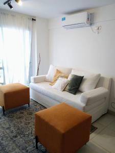 a living room with a white couch and two ottoman at Avenida Premium: Confort y Vistas Excepcionales in San Salvador de Jujuy