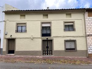 a white house with black barred windows on a street at Casa Sina in Riópar