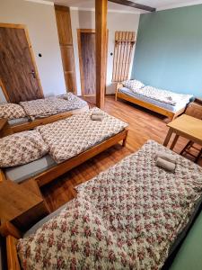 three beds in a room with wooden floors at Karkonoska Drewniana Chata in Kamienna Góra