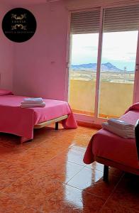 a room with two beds and a large window at Hotel y Restaurante Costas in Fortuna