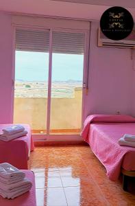 a pink room with two beds and a window at Hotel y Restaurante Costas in Fortuna