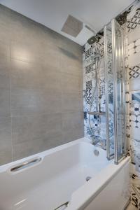 La salle de bains est pourvue d'une baignoire blanche et d'une douche. dans l'établissement Lionsgate View - luxury apartment opposite Alnwick Castle, à Alnwick