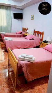 a group of four beds in a room with pink sheets at Hotel y Restaurante Costas in Fortuna
