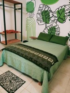 ein Schlafzimmer mit einem Bett mit einer grünen Bettdecke in der Unterkunft Calli Cintli in Tepoztlán