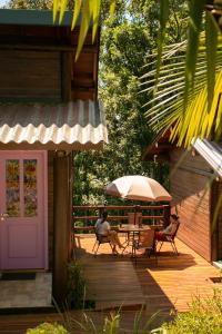 une terrasse en bois avec une table et un parasol dans l'établissement Chalé Esmeralda na Amarte perto do Templo Budista, à Três Coroas