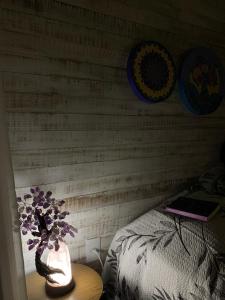 a bedroom with a vase with purple flowers on a table at Chalé Esmeralda na Amarte perto do Templo Budista in Três Coroas +4 photos