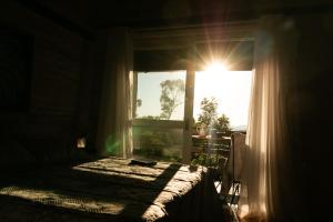 - une chambre avec un lit et une fenêtre baignée de lumière naturelle dans l'établissement Chalé Esmeralda na Amarte perto do Templo Budista, à Três Coroas