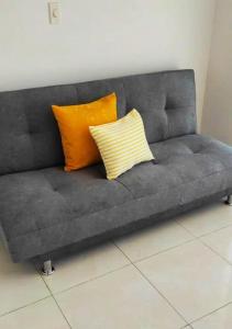 Un sofá gris con dos almohadas naranjas. en Acogedor Apartaestudio cerca al aeropuerto, en Cúcuta