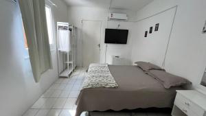una piccola camera con letto e televisore di Pousada Mar & Sol a Fortaleza